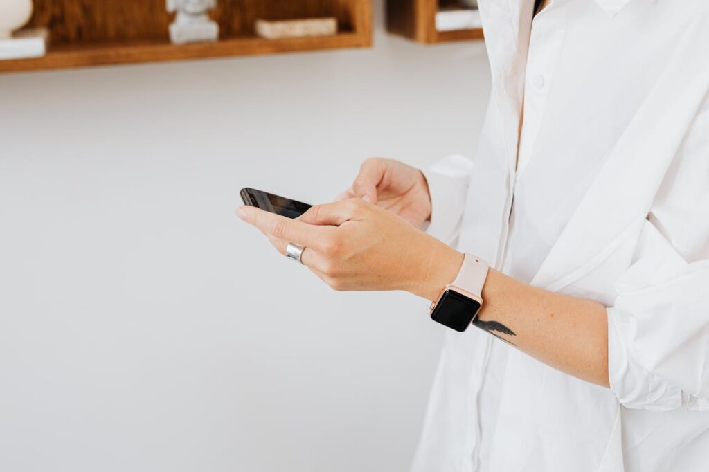 Close-up of person in white shirt using smartphone, wearing a smartwatch.